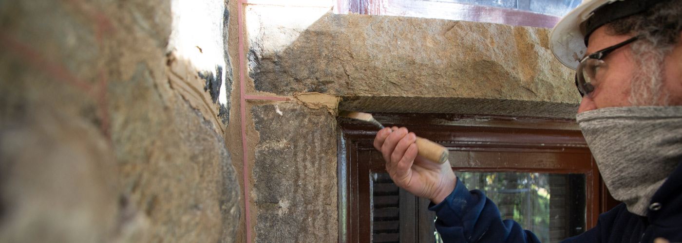 Brent Ryder applying mortar with a trowel in the corner of a window set in a stone wall