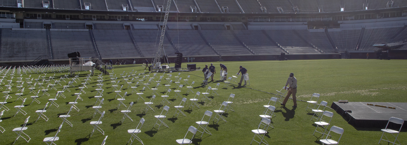 Facilities Management employees arranging chairs across the turf in Scott Stadium for Final Exercises ceremonies