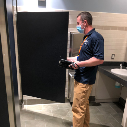 Michael Pouliot conducts an inspection of a restroom stall
