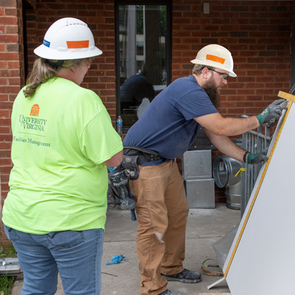 Tracy Porter measuring drywall and Bonnie Barnett looking on standing in the foreground