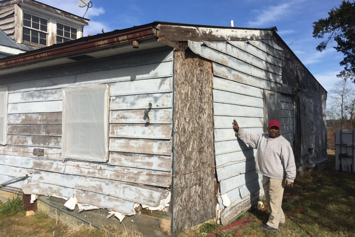 Before photo of the damaged siding of a house repaired by FM employees as part of the Building Goodness in April program