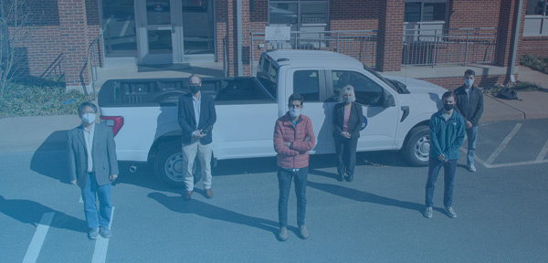 Top-down photograph of the Fleet team with engineering students, spaced out next to a Fleet pickup truck.