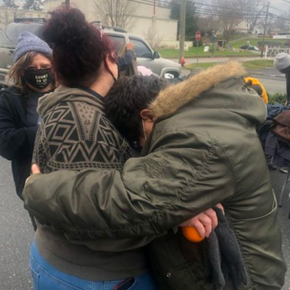 A woman in a donated winter coat hugs another woman