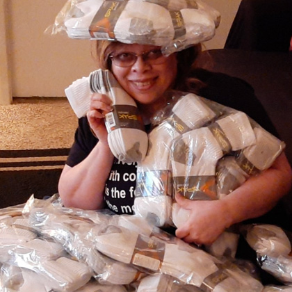 Adrienne Young holds a pile of packaged socks and balances a package on her head