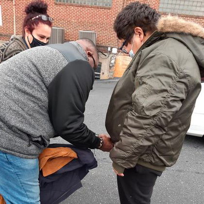 A man checks the zipper on a winter coat worn by a woman