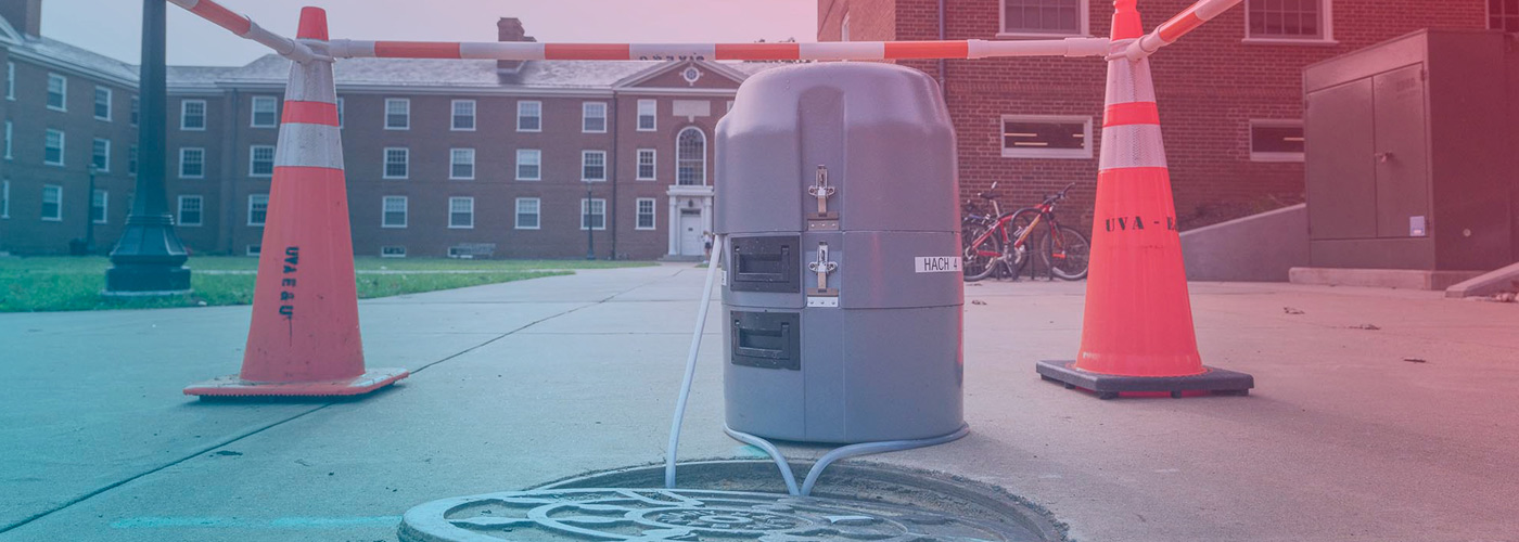 A wastewater autosampler beside an open manhole outside UVA residence halls