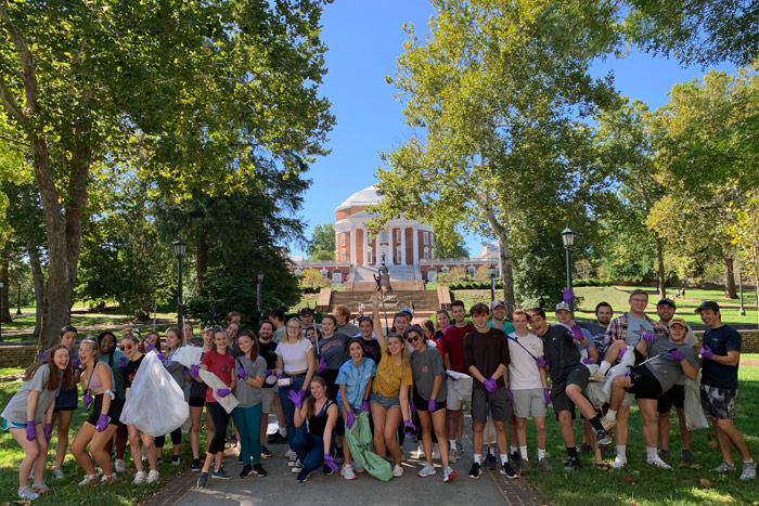A large group of student volunteers posing on The Lawn with The Rotunda visible in the background