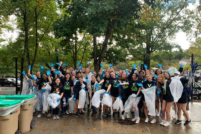 Many volunteers for the Green Game event wearing latex gloves pose with trashbags