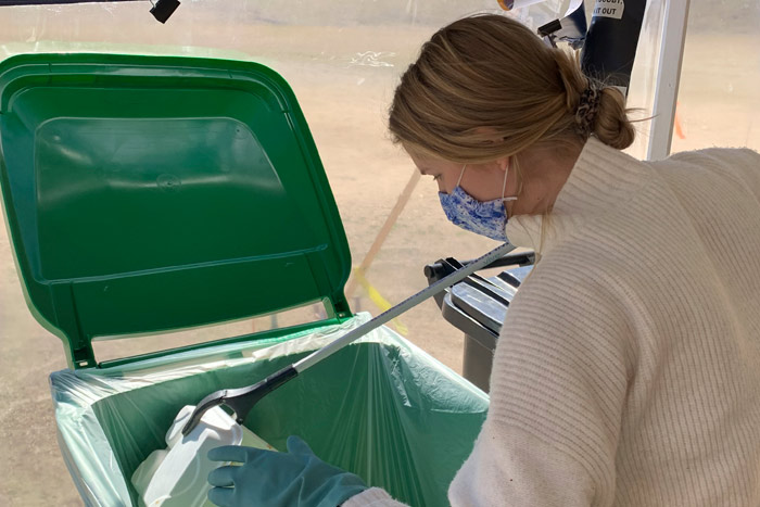 A student using a claw grabber to put waste into a recycle bin