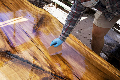 An FM employee smoothes out epoxy on a slab of poplar
