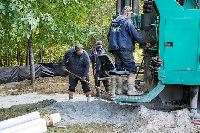 Energy & Utilities employees shoveling sediment and operating a boring machine