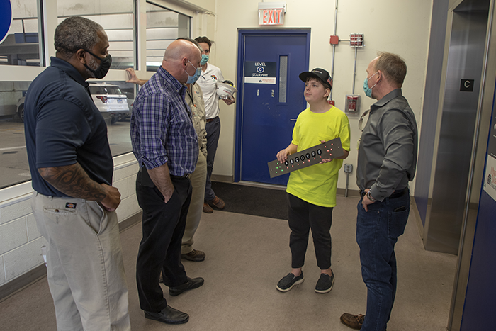 Staff members chat with teen holding an elevator fixture