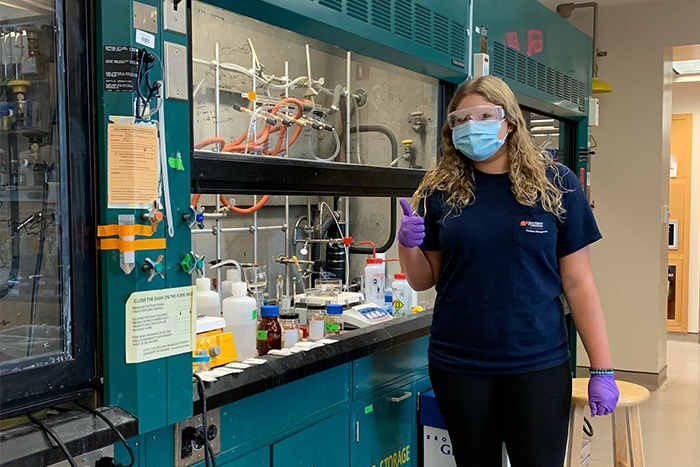 Olivia Regehr in lab PPE giving a thumbs-up