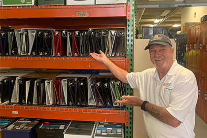 Sonny Beale displays metal shelves full of binders